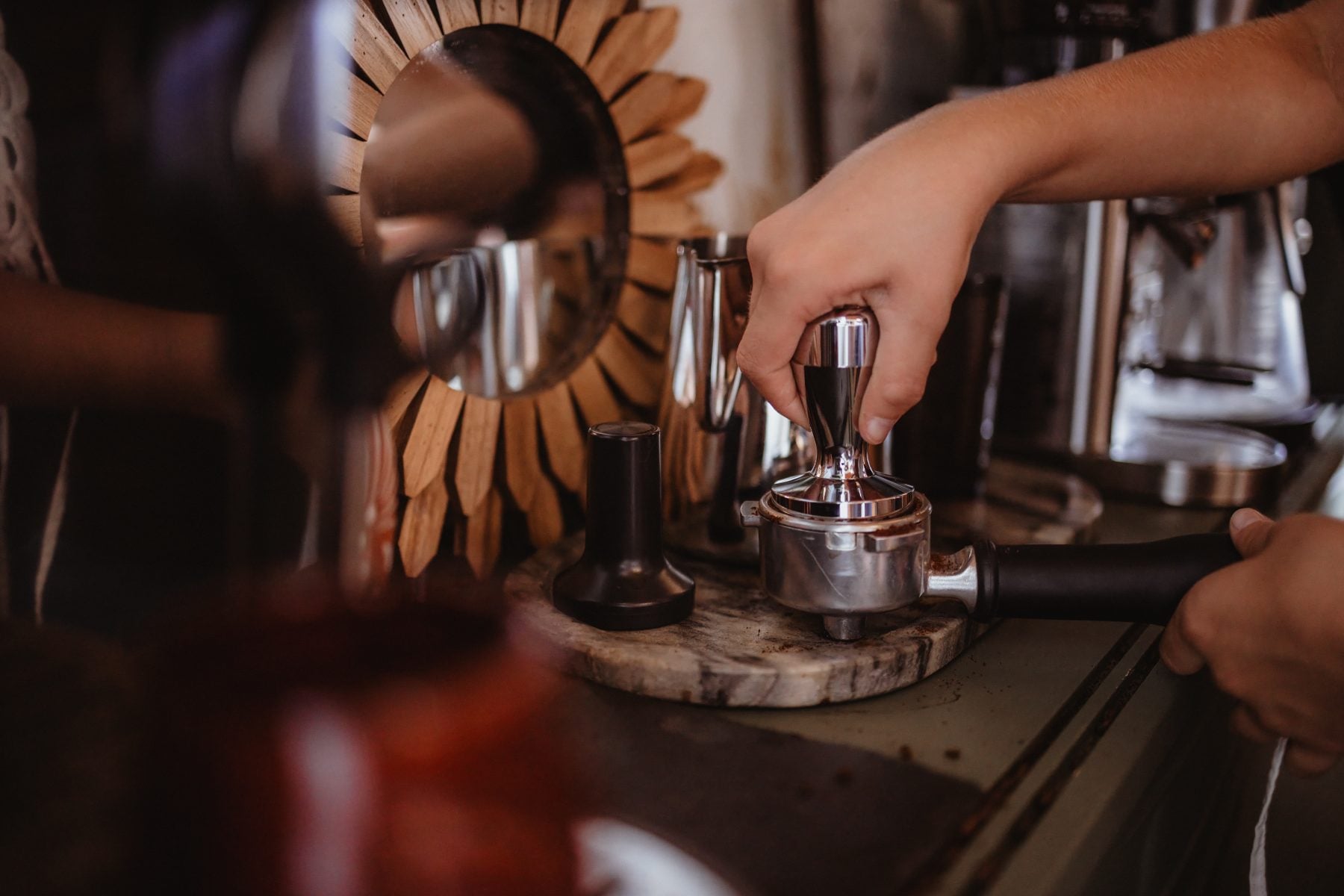 Barista tamping espresso grounds into portafilter at home coffee bar