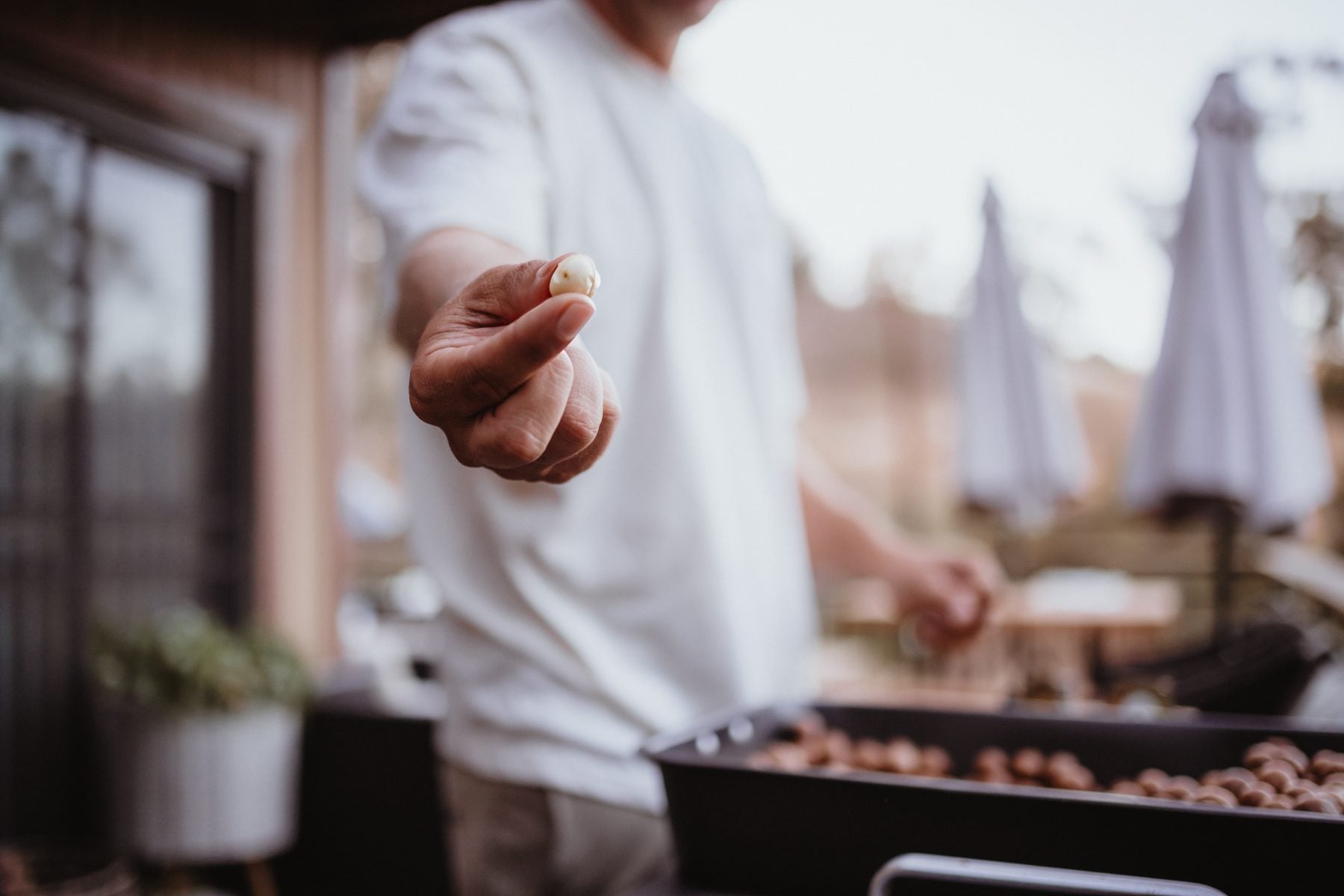 Man holds a fresh berry over a smoking outdoor grill on patio