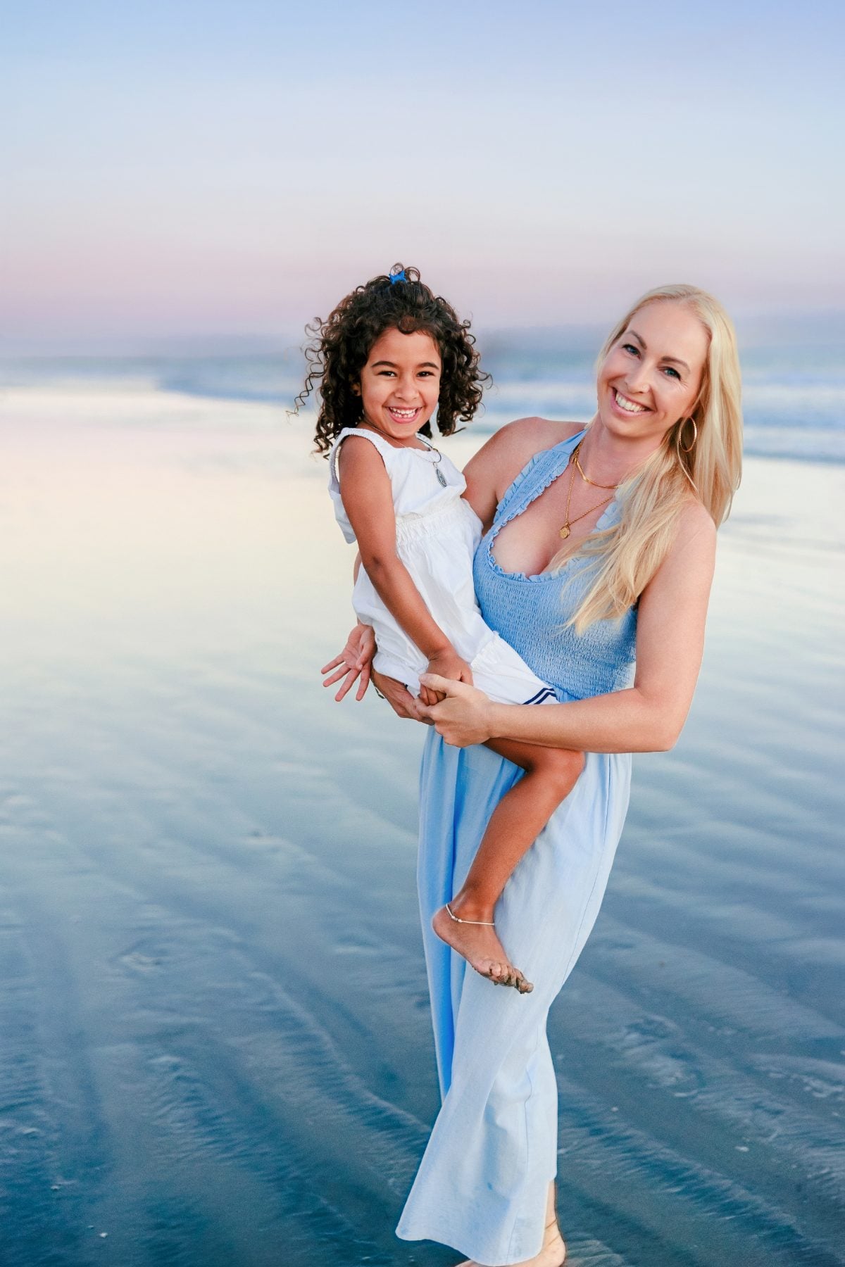 Mom holding smiling daughter on Coronado Beach at sunset, San Diego family photographer