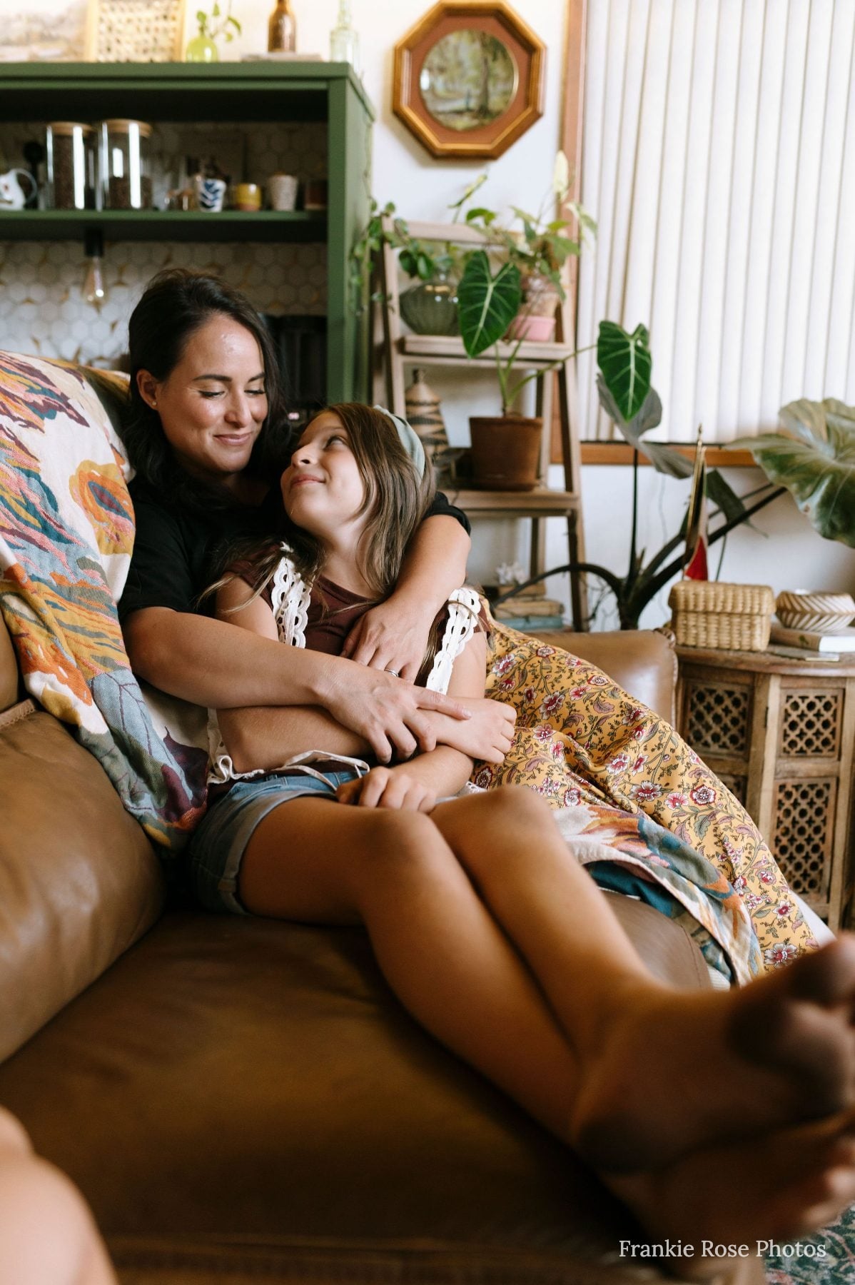 Mother embraces her daughter on a leather couch in their living room