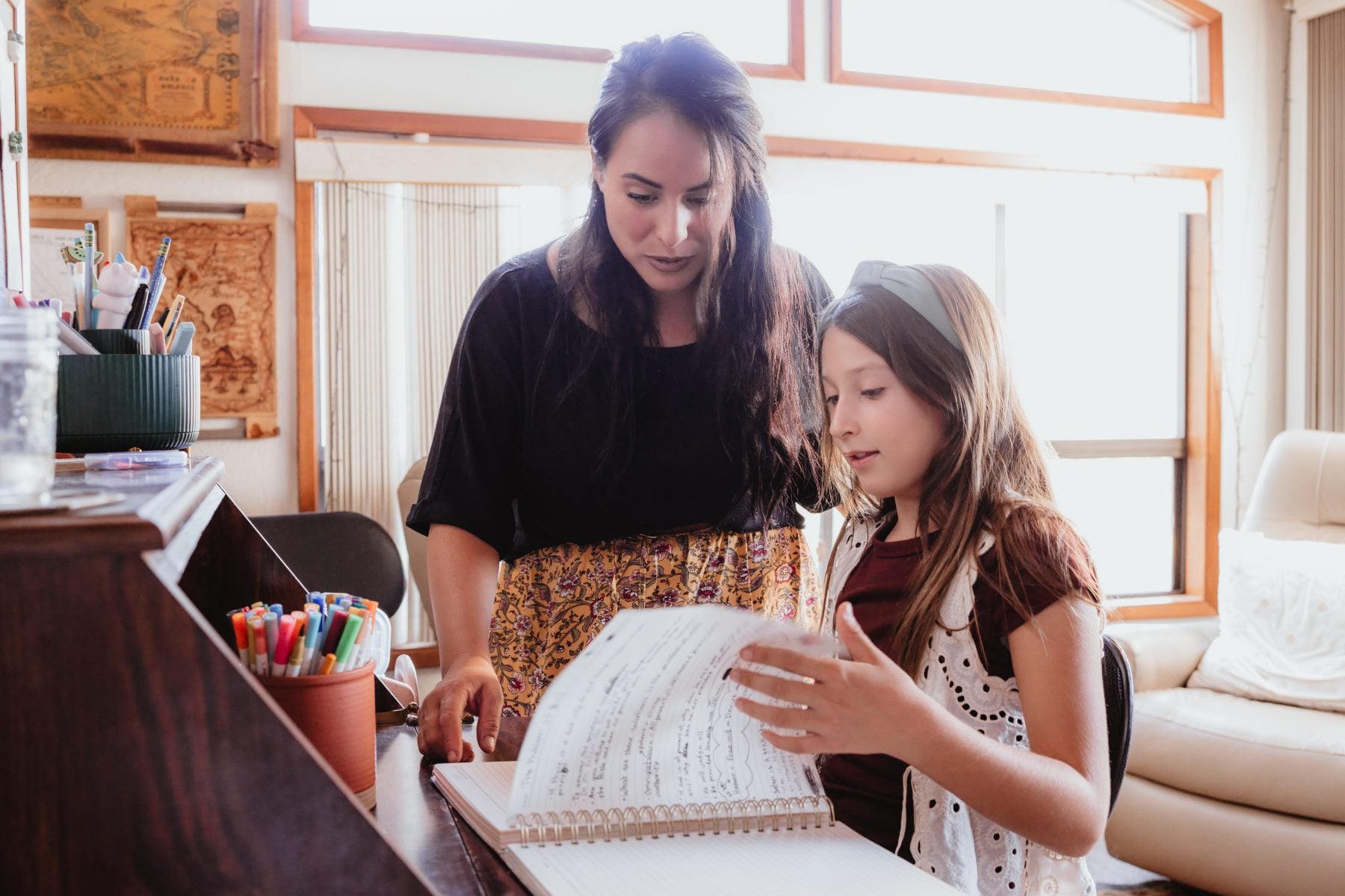 Mother and daughter reading sheet music together at piano, Lakeside home