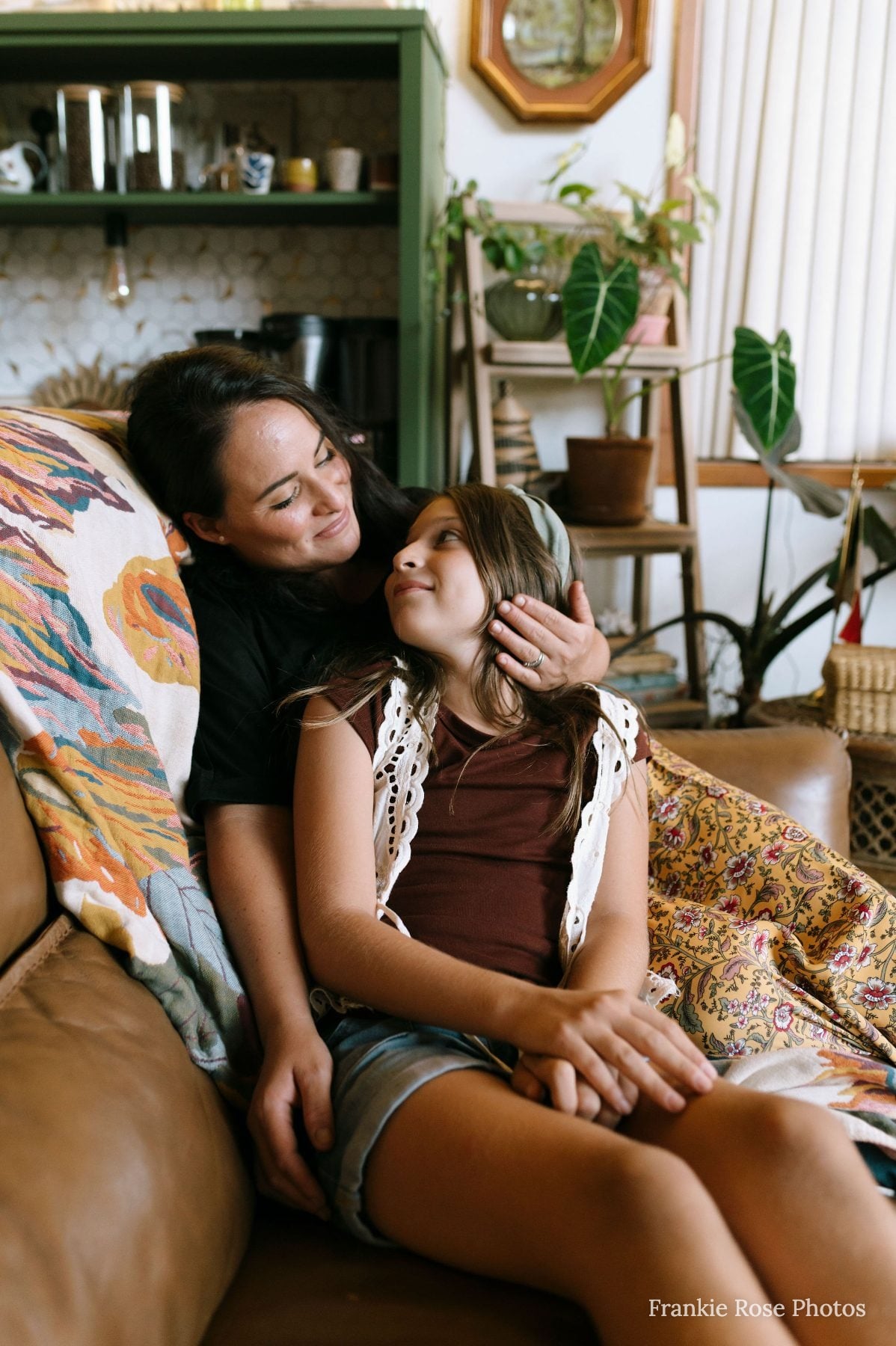 Mother tenderly touches her daughter's cheek while sitting on the couch