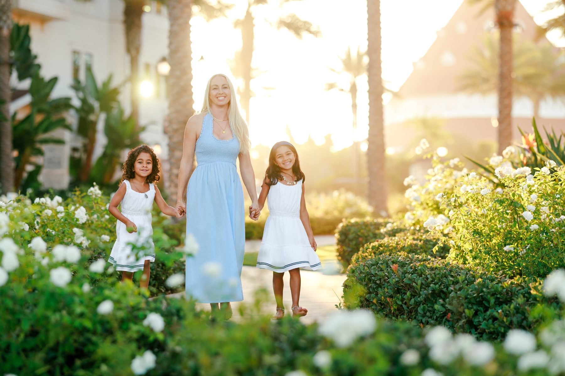 Mother and two daughters stroll through a blooming garden at Hotel del Coronado