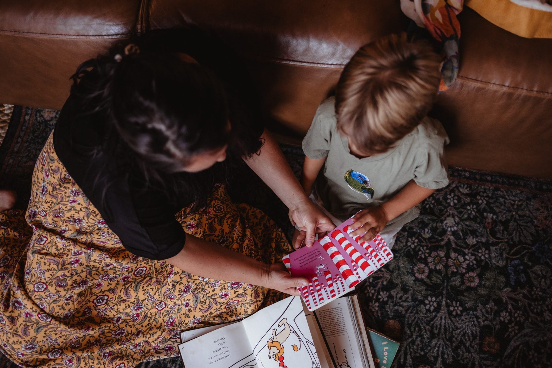 Mother helps her son with a coloring book on the floor