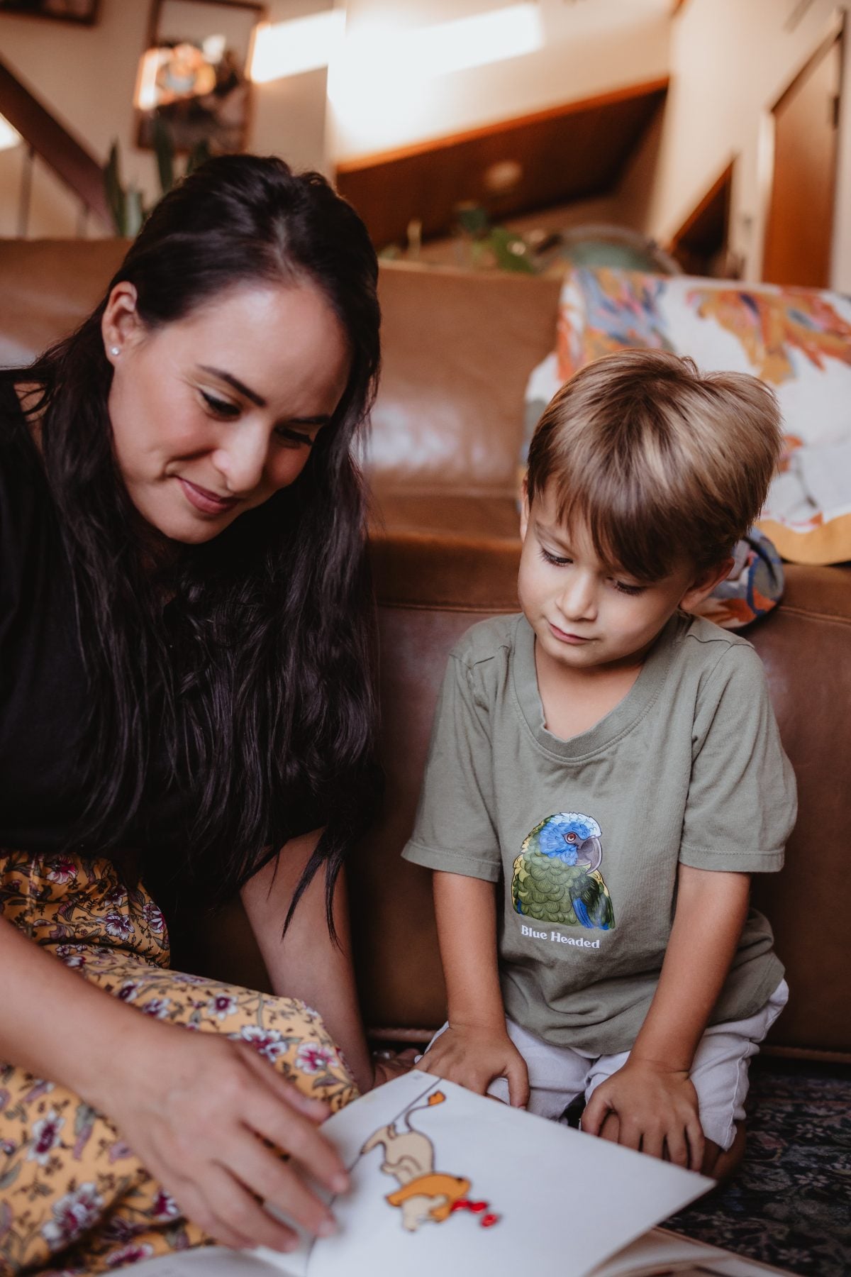 Mother and young son reading a picture book together on the couch