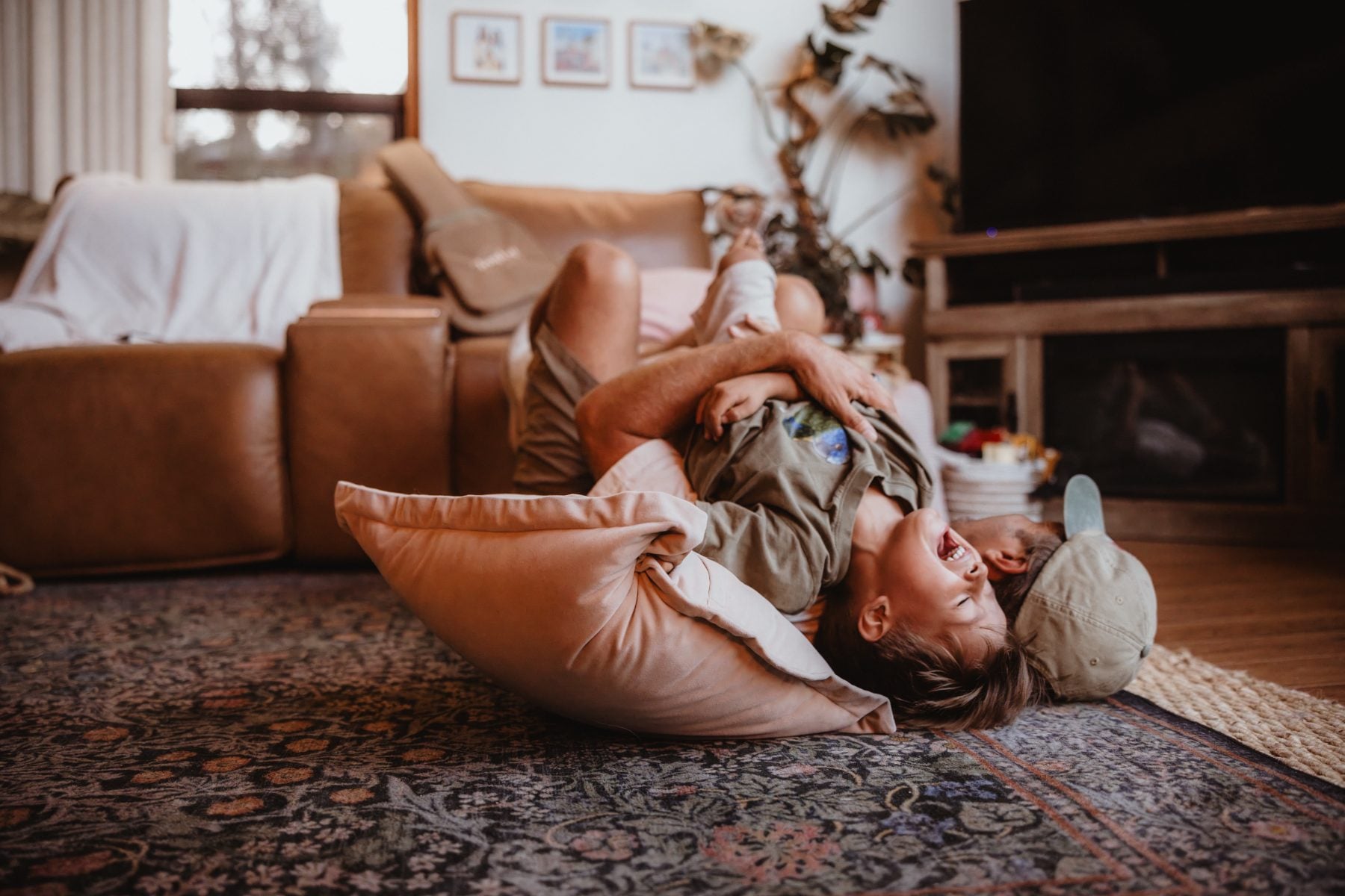 Mom and son lie upside down together on a cushion on rug