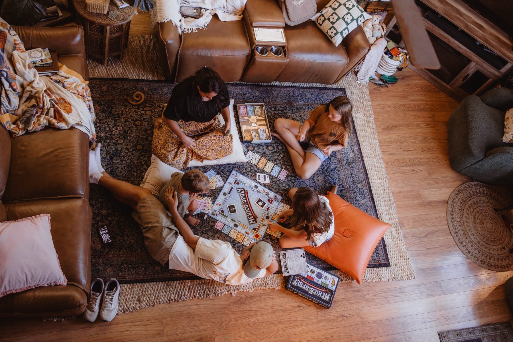 Overhead view of family playing board game on living room rug