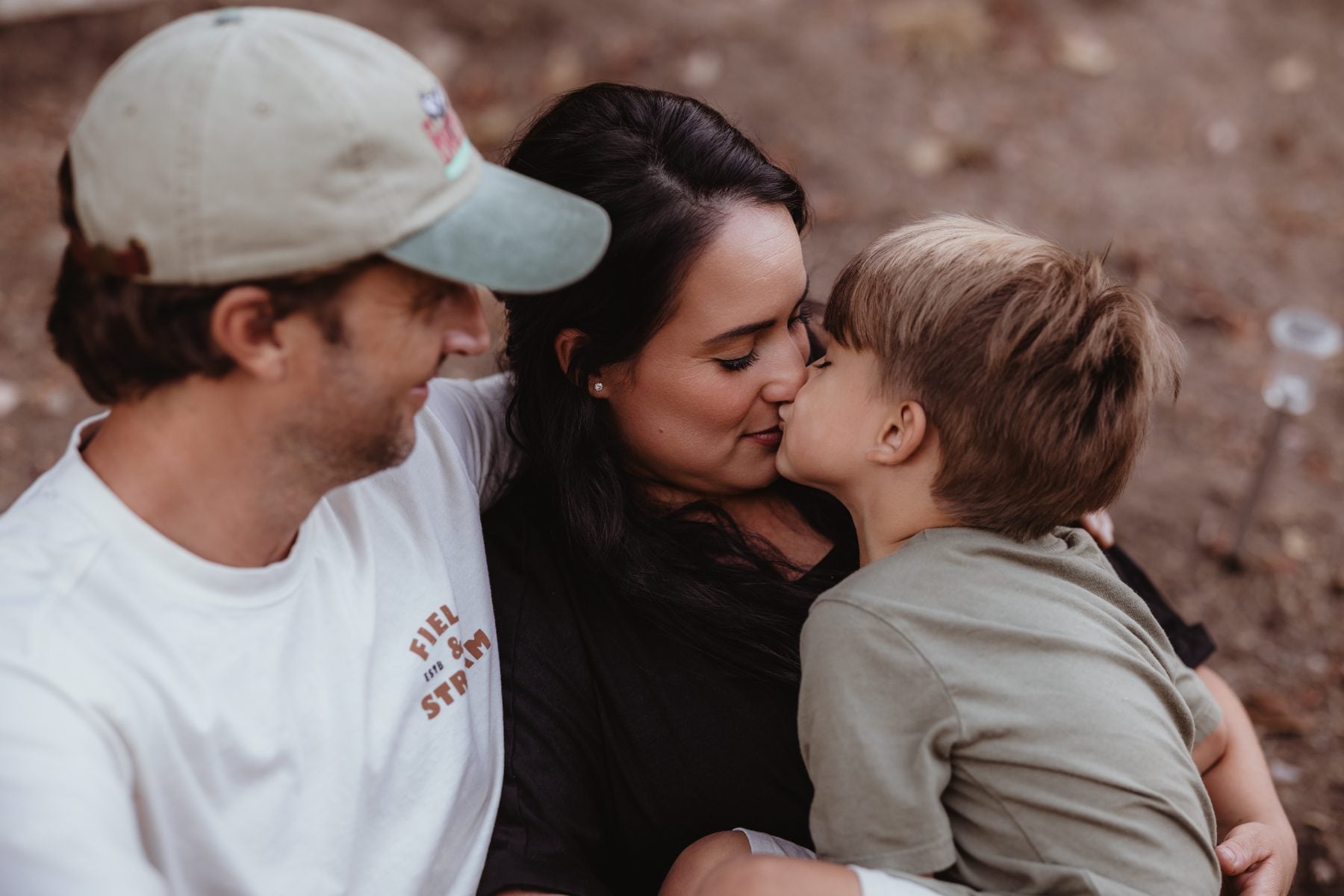 Parents share a nose-to-nose moment with their son outdoors in Lakeside