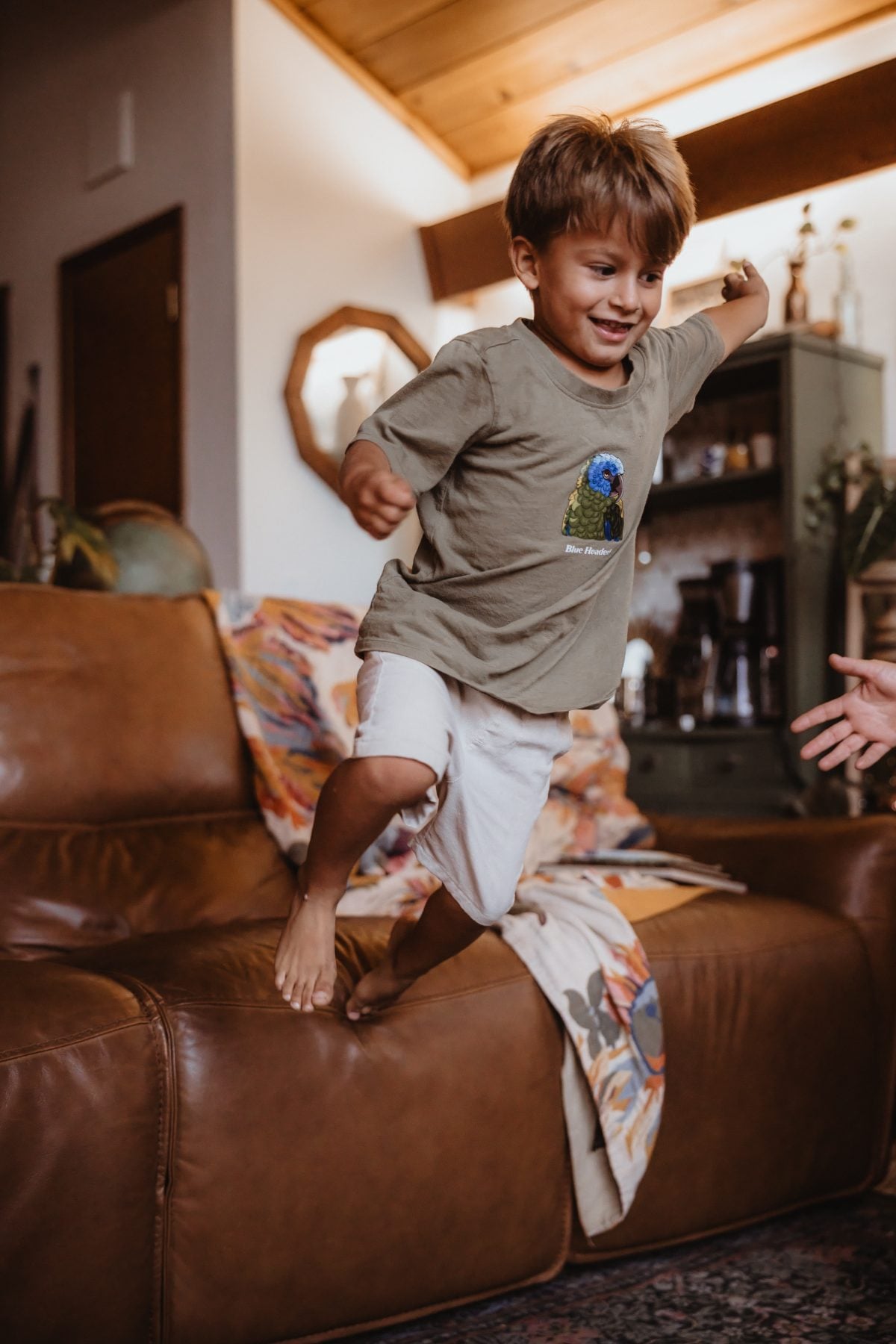 Boy jumps off leather couch mid-play, captured by San Diego family photographer