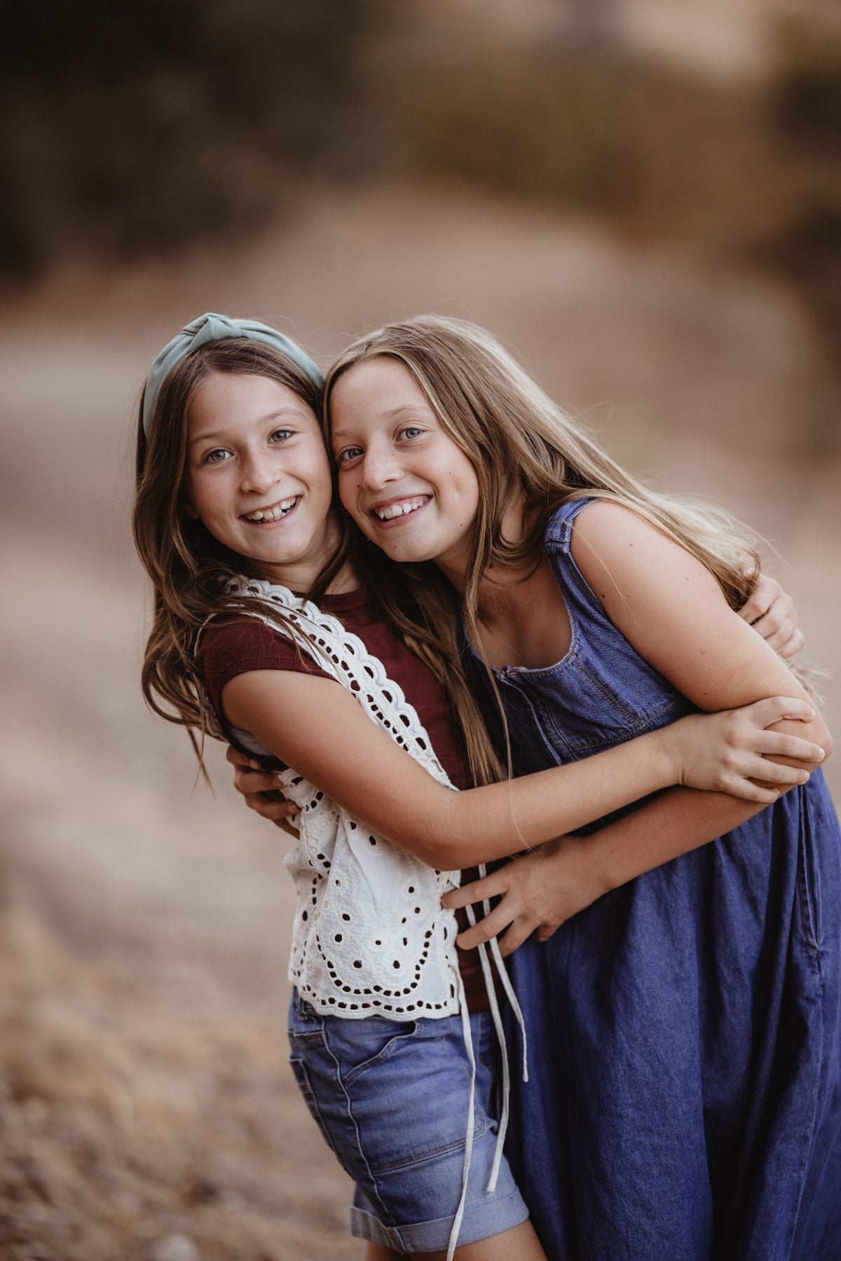 Two sisters hug and laugh together outdoors near Lakeside