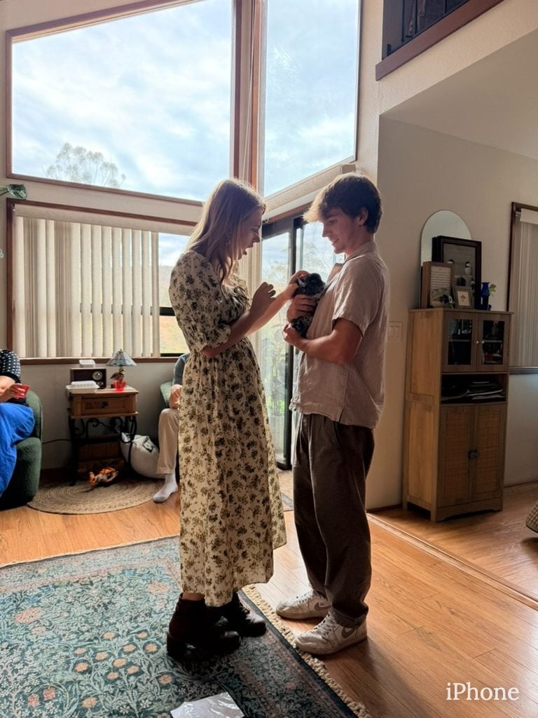 Teen siblings share a laugh while looking at camera in sunlit living room
