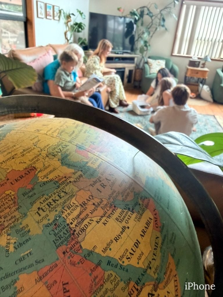 Vintage globe shows Middle East with family reading blurred in background