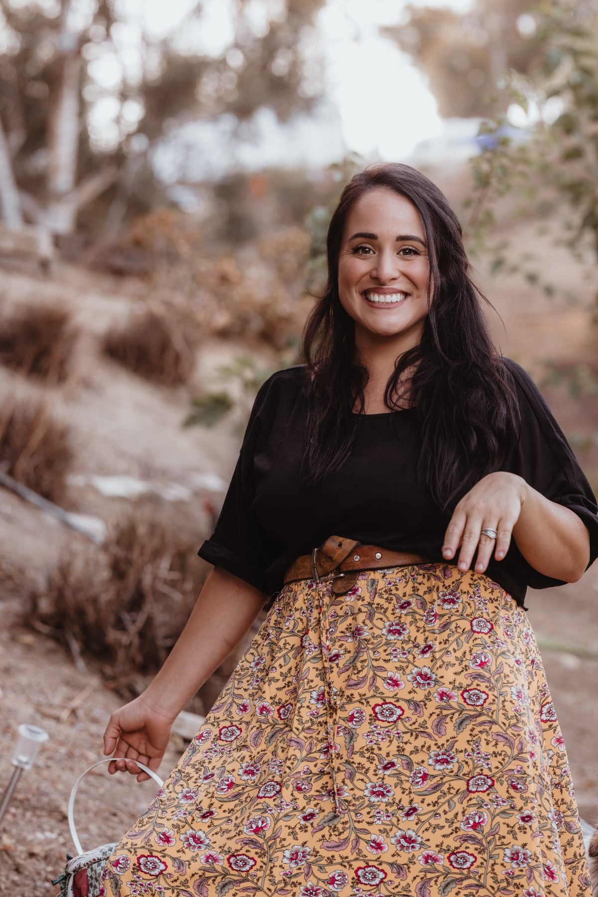 Woman in floral skirt smiling outdoors on dirt trail in Lakeside