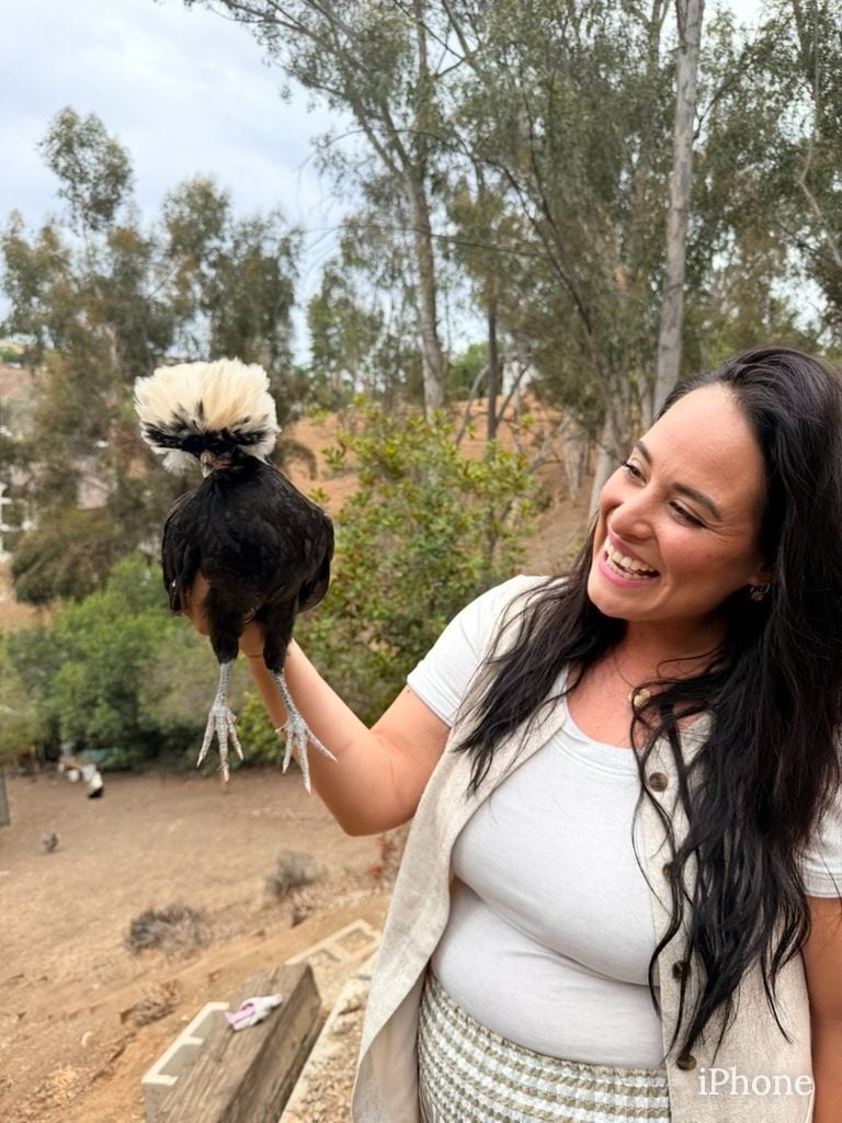 Smiling woman holds fluffy black and white chicken outdoors in Lakeside